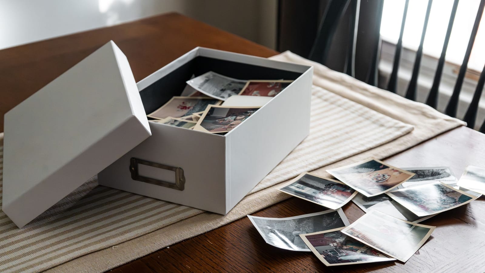 Open box of old family photographs spread across a wooden table