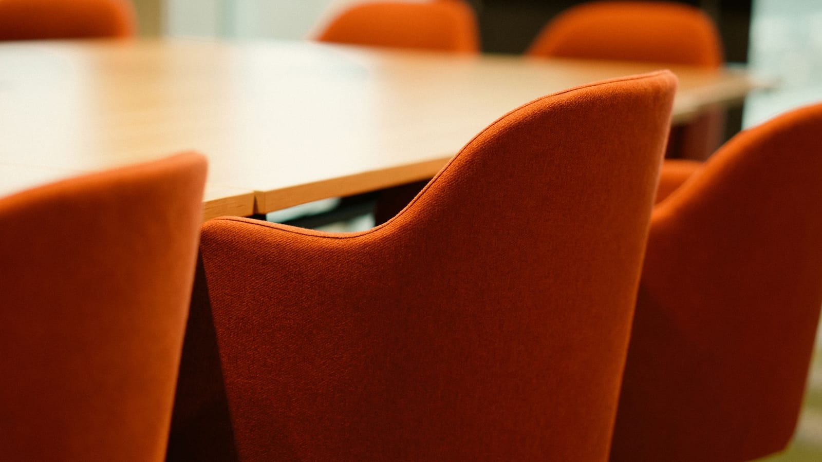 Empty meeting table surrounded by orange upholstered chairs