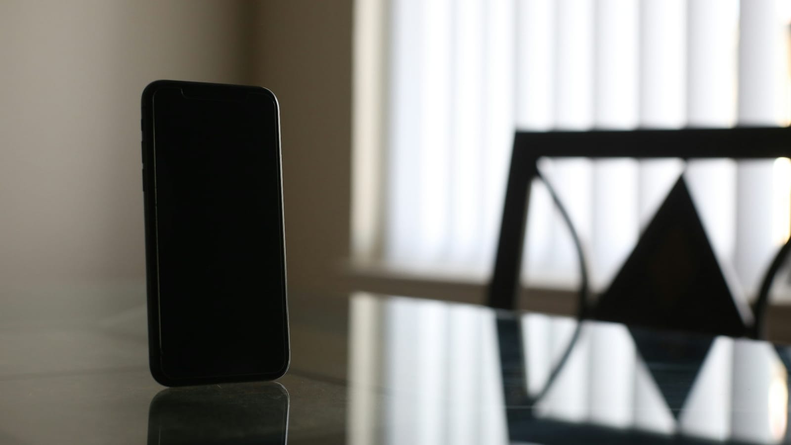 Cam masa üzerinde ekranı kapalı siyah akıllı telefon