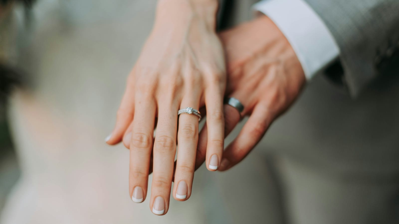 A couple's hands side by side, both wearing wedding rings