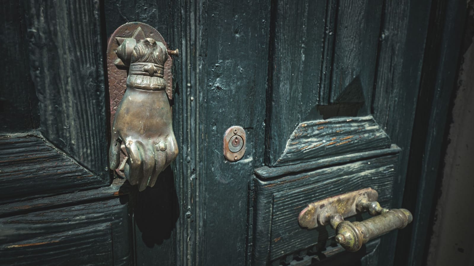 Brass hand-shaped knocker on an old wooden front door