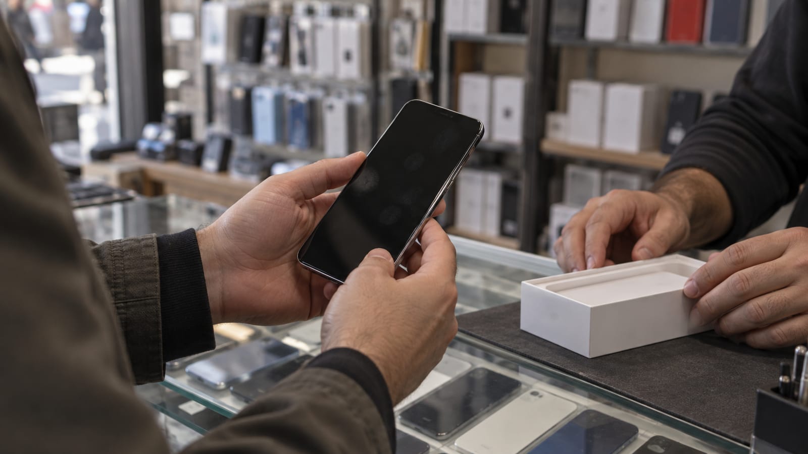 Telefon dükkânında markasız bir cep telefonunu inceleyen alıcının elleri