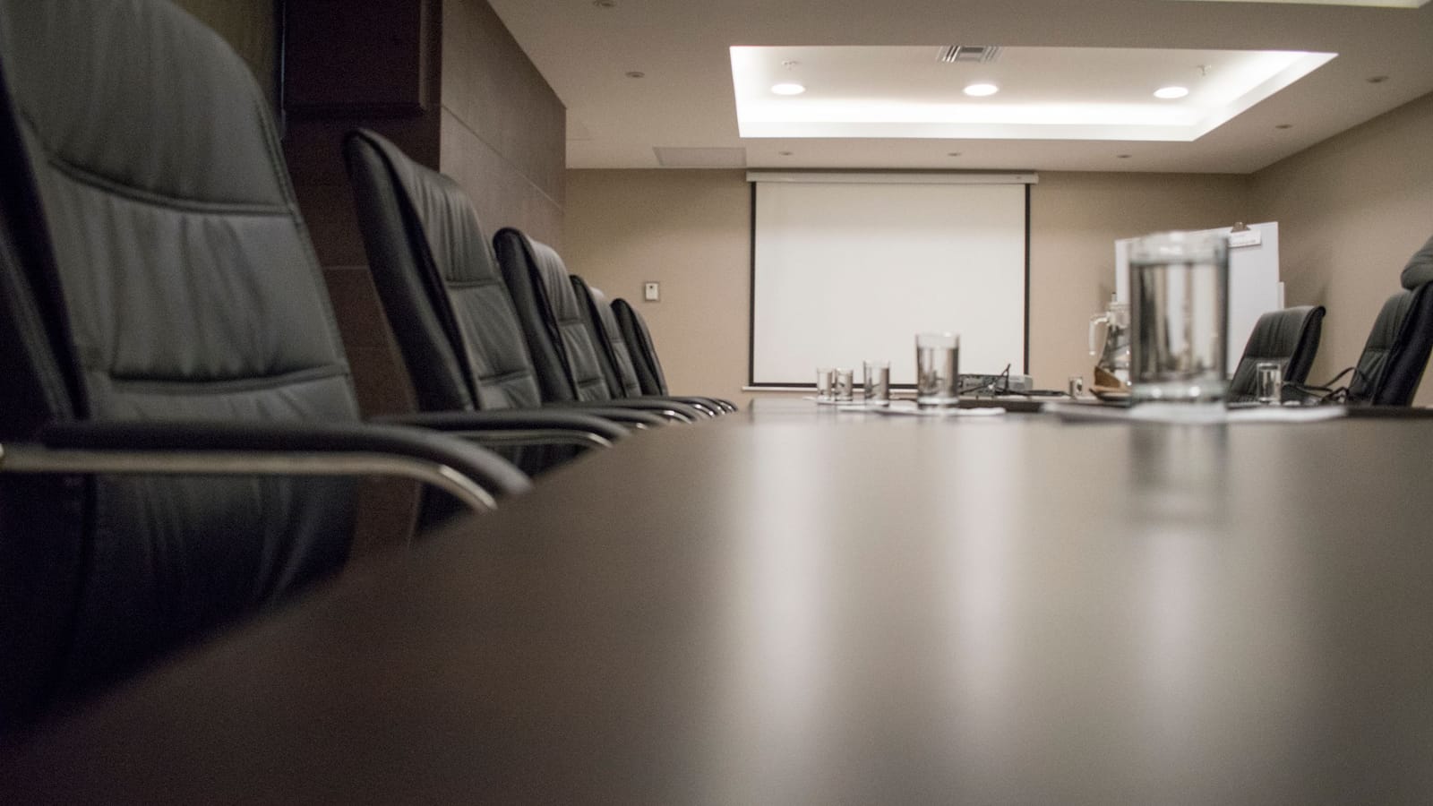 Long empty boardroom table lined with leather chairs